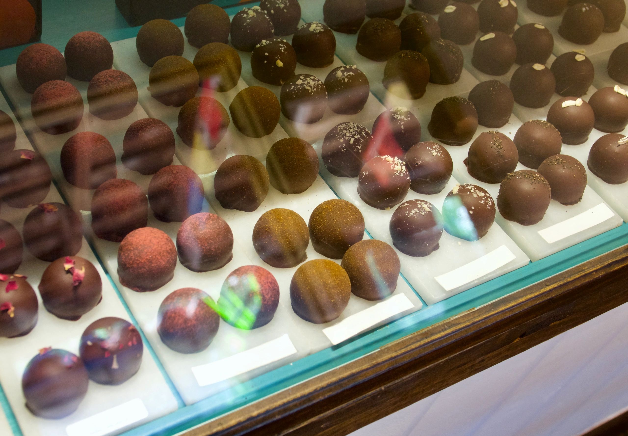 Assortment of chocolate truffles on display behind glass